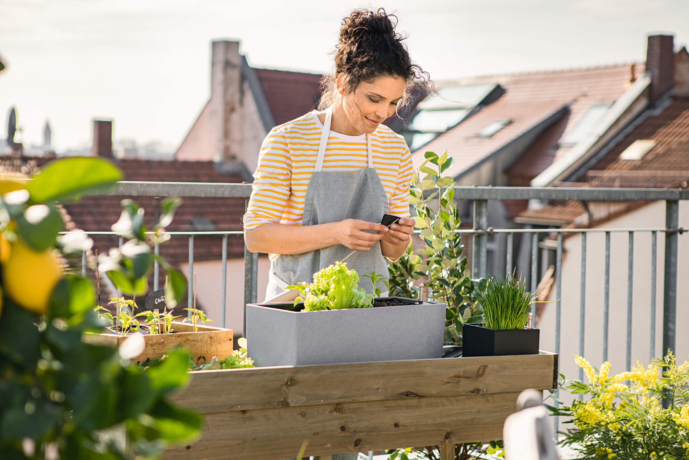 woman outside on balcony watering plants